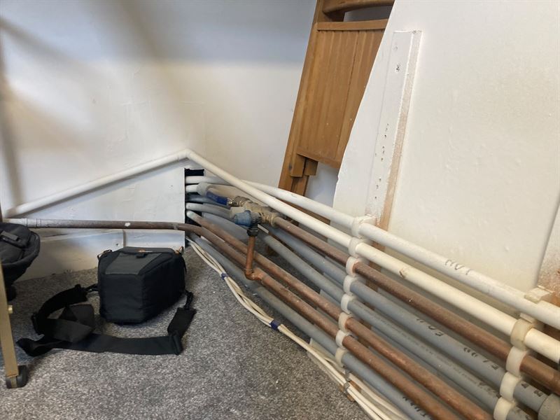 Wider view of existing pipework routed near floor level