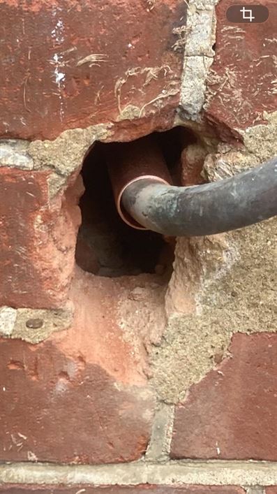 Close view of the gas pipe penetration through exterior brickwork