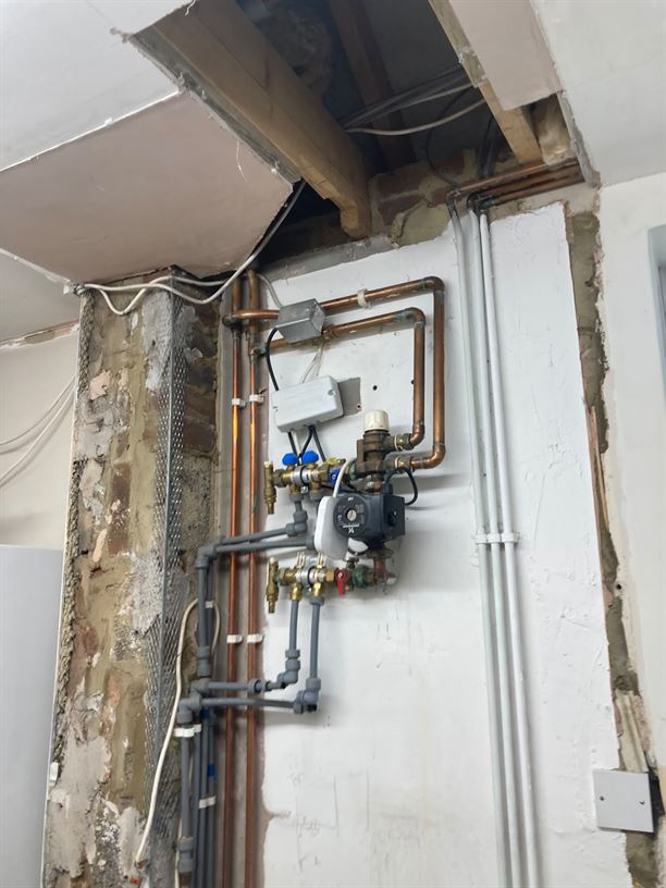 Underfloor heating equipment and exposed pipework during the Radlett utility room project