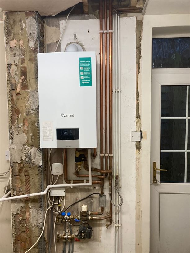New Vaillant boiler and exposed pipework during utility room remodelling