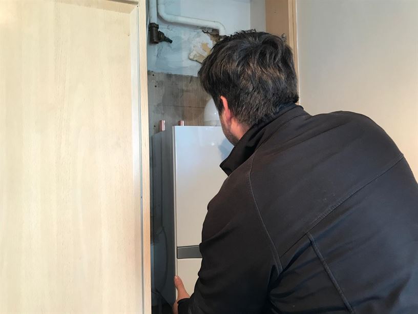 Engineer fitting the new boiler within the existing kitchen unit